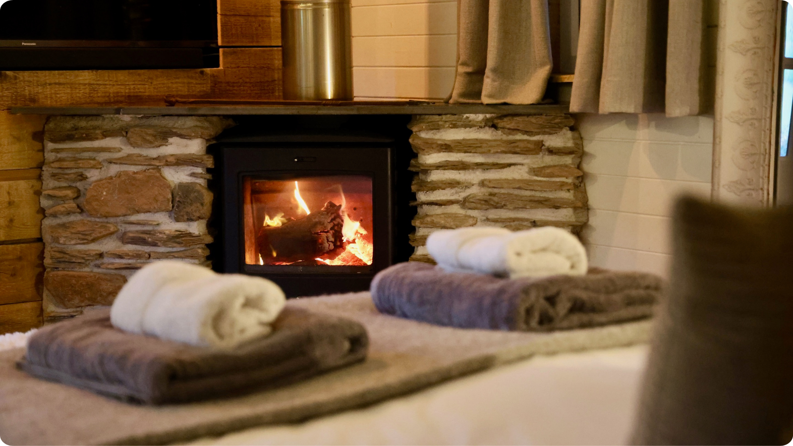 Folded towels in front of a lit wood-burning stove