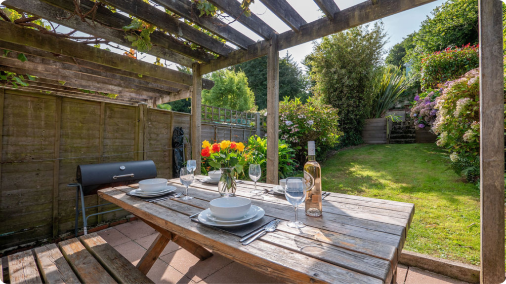 Garden dining table set beneath a wooden pergola